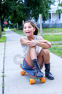 坐在路边滑板上的女孩肖像图片