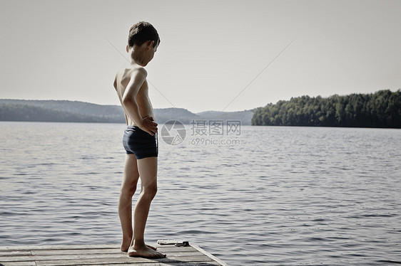 男孩站在码头向下看湖图片