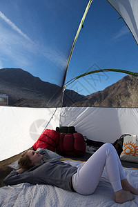 年轻女从美国加利福尼亚州安萨博雷戈沙漠州公园的帐篷里向外看图片
