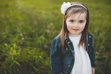 带着白色头饰的小女孩在草坪上微笑背景图片
