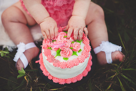 坐在草地上用手摸生日蛋糕的女婴图片