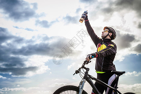成年男子山中骑自行车的成年男子举起水瓶庆祝图片