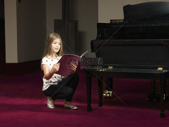 女孩在舞台上蹲着看钢琴乐谱图片
