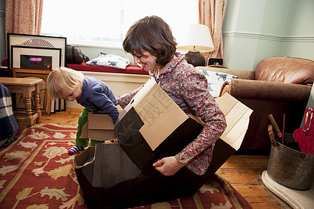 母亲和儿子在客厅玩纸板盒图片
