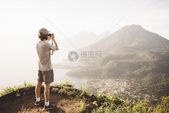 用数码相机拍摄照片的青年男子图片