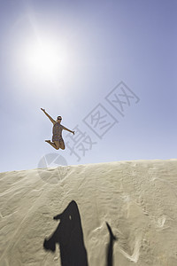 海滩上跳跃的年轻女子图片
