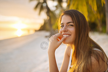日落时在海滩的年轻女子图片