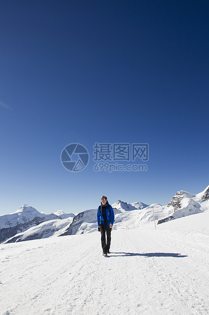 在雪覆盖的山丘中徒步旅行的运动者图片