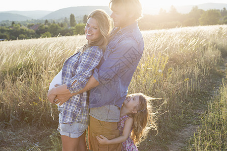 怀孕的年轻夫妇和女儿在野外拥抱对方图片