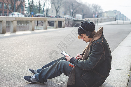 坐在路边使用平板的年轻男子图片