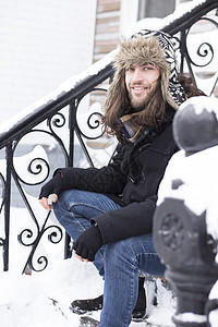 坐在被雪覆盖的台阶的年轻人肖像图片