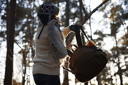 成熟的女背包客在森林里举起背包图片