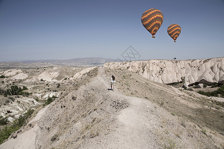 土耳其安纳托利亚卡帕多西亚岩层景观中的女游客和热气球图片