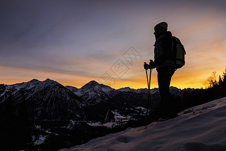年轻女远足者在黄昏时从山边向外看风景图片