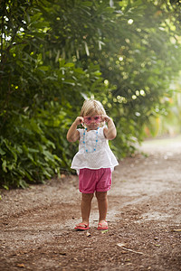 海滩小径上一名蹒跚学步的女孩戴着粉红色太阳镜图片