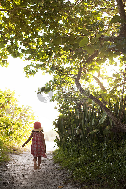 戴着太阳帽的赤脚女孩沿着林地海滩小径行走图片
