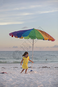 海滩上女孩在五颜六色的沙滩伞旁奔跑图片