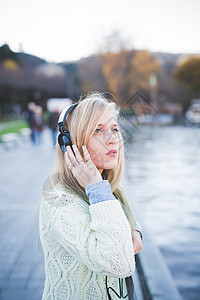 意大利科莫湖畔一名年轻女子一边听着耳机一边抬头看图片