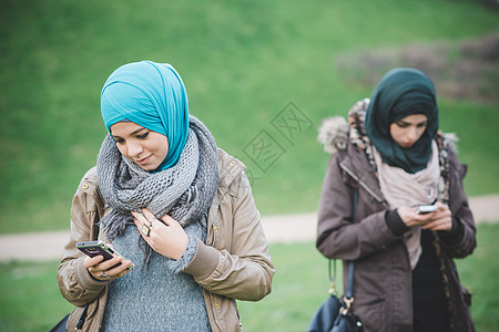 公园里的两位女朋友在公园里阅读智能手机短信图片