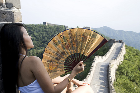 北京长城上手持扇子的中年女游客的后视图图片