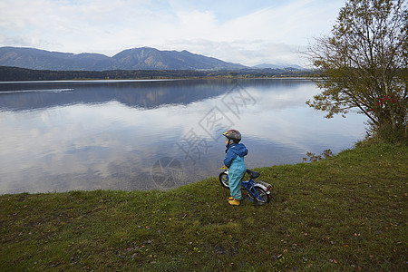 湖边自行车在湖边站着骑自行车的小男孩背景