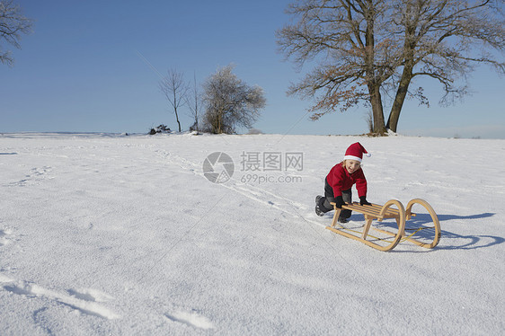 小男孩把雪橇推下山坡图片