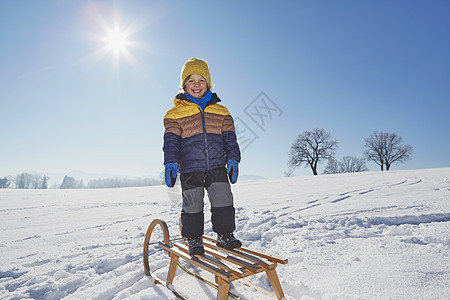 年轻男孩的肖像站在雪地的橇上图片