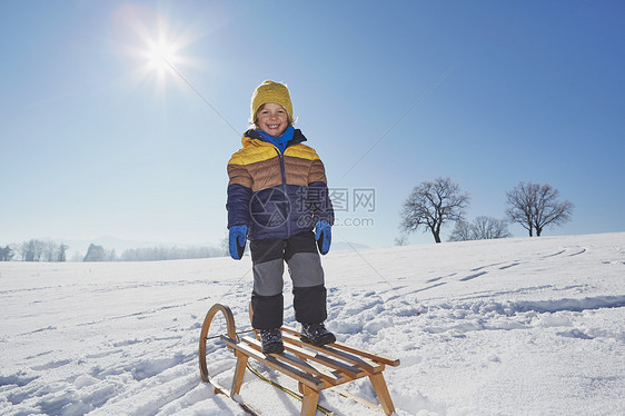 年轻男孩的肖像站在雪地的橇上图片