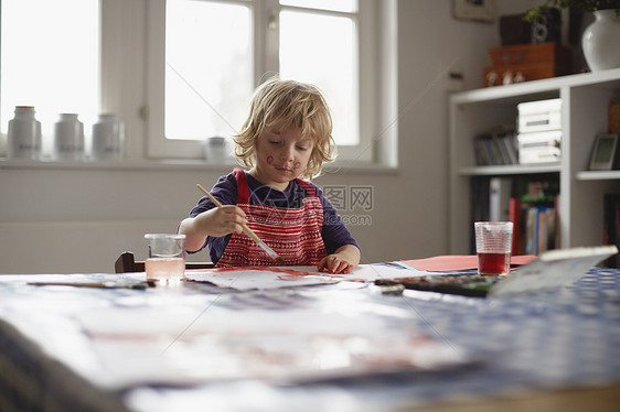 坐在桌边的年轻男孩画图片