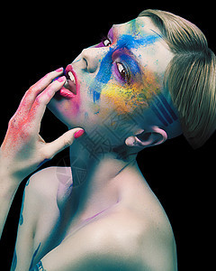 年轻妇女触摸面孔彩色粉和脸上涂油漆图片