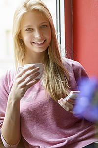 女青年在咖啡馆使用智能手机时喝咖啡的肖像图片
