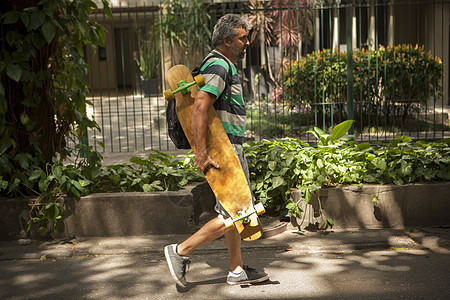 在人行道上漫步的成年人携带滑板巴西里约热内卢图片