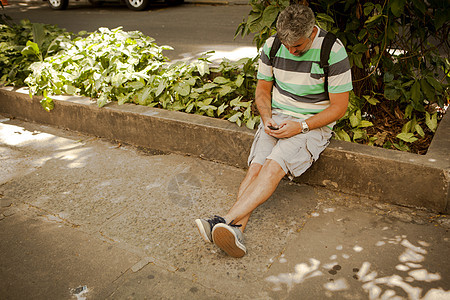 坐在智能手机人行道短信上的成年男子巴西里约热内卢图片