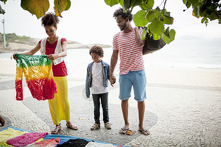 巴西里约热内卢伊帕马海滩人行道摊铺上选择毛衣的夫妇和儿子图片