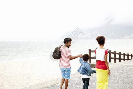 巴西里约热内卢伊帕内马海滩一对夫妇和儿子手牵手漫步的后视图图片