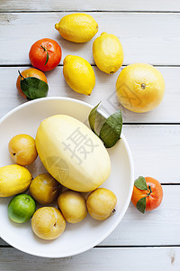 桌上白碗中里的各种柑橘类水果图片
