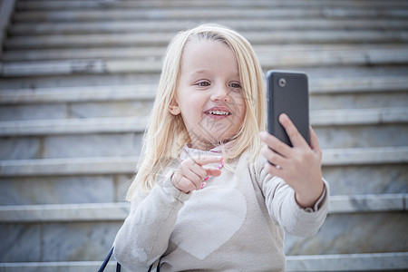 楼梯上的年轻女孩正在使用智能手机自拍图片