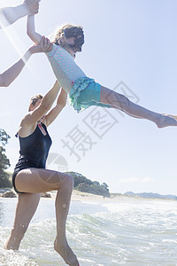 两名成年夫妇在海浪中举起女孩图片