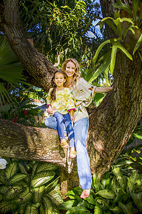 母亲和女儿坐在花园树枝上图片