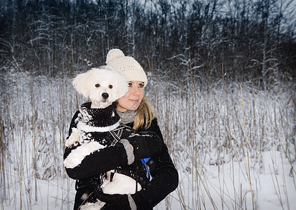 在雪地中抱着宠物狗的女人图片