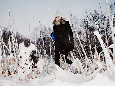 在雪地中牵着宠物狗的女人图片