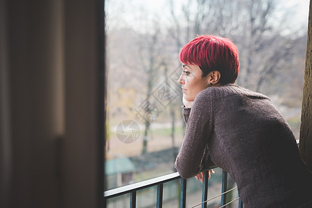 拄着栏杆的忧郁年轻女士图片