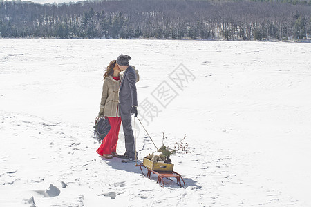 带着雪橇站在雪地上接吻的成年夫妇图片