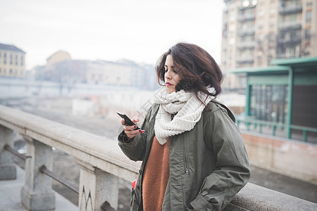 年轻女性靠在栏杆上使用手机图片