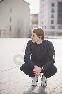 蹲坐在广场休息的男青年图片素材