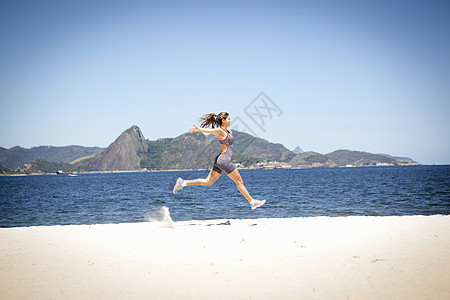 在海滩上跳跃的年轻女子图片
