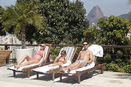 巴西里约热内卢按游泳池分列的年轻家庭日光浴图片