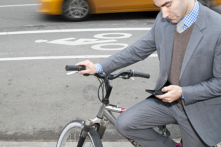 依赖自行车看智能手机的青年商人图片