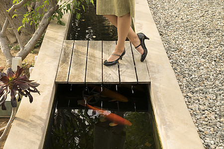 女子走过花园鱼塘中局部腿部图片