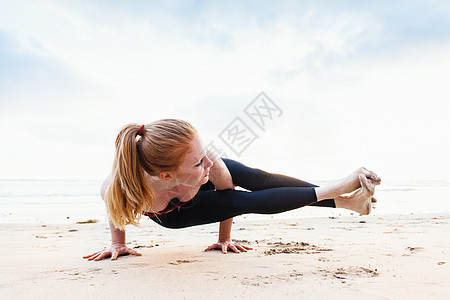 海滩上做瑜伽的年轻女性图片